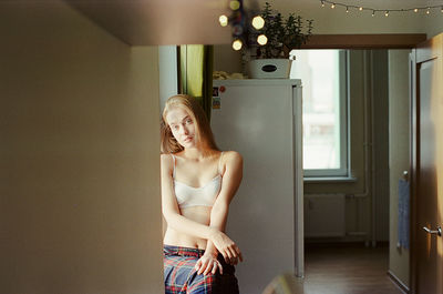 A woman stands in front of a window in an apartment