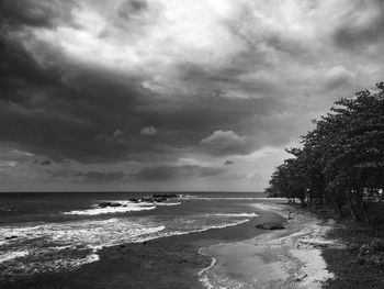 View of calm beach against cloudy sky