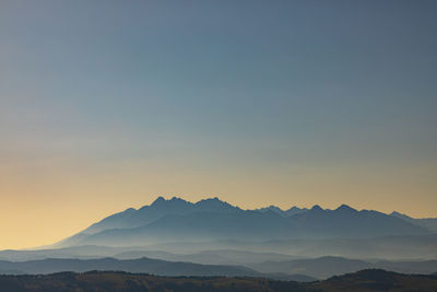Scenic view of silhouette mountains against clear sky during sunset