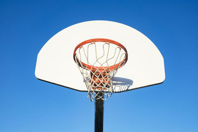 Low angle view of basketball hoop against clear blue sky