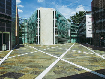 Empty road by buildings against sky in city