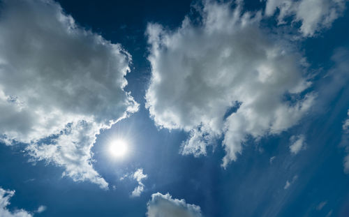 Low angle view of sunlight streaming through clouds