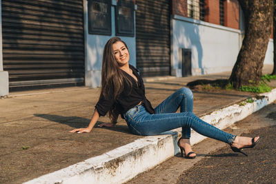 Portrait of young woman against building