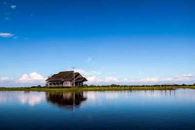 Scenic view of lake by building against blue sky