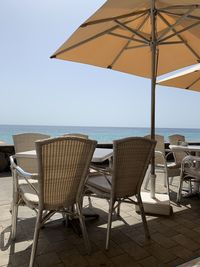 Chairs and table at beach against sky