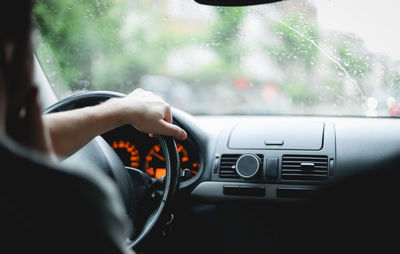 A young caucasian guy keeps his hand on the steering wheel while driving a car.