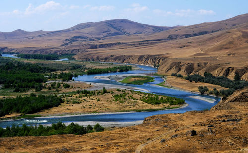 Scenic view of river by mountains against sky