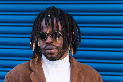 Portrait of man wearing sunglasses against wall