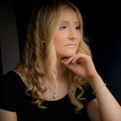 Beautiful young woman looking away over black background