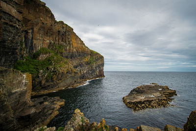 Rock formations by sea against sky