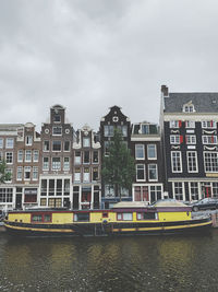 Buildings by river against sky in city