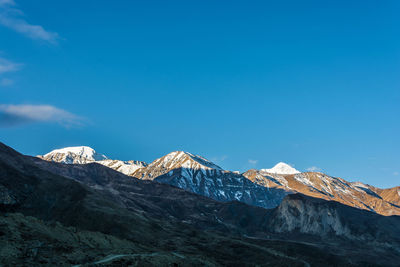 Scenic view of snowcapped mountains against blue sky