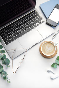 White office desk table with laptop, supplies and coffee cup. space for text