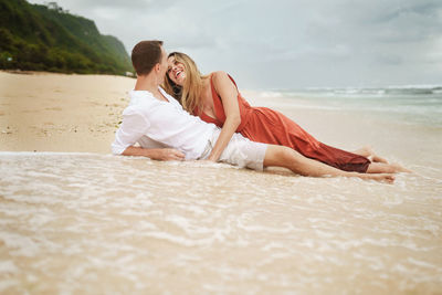 Happy young couple romancing while lying at shore