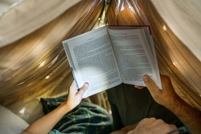 Father and son playing and reading in a kid tent at home.
