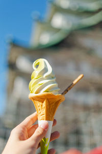 Cropped hand holding ice cream cone in city