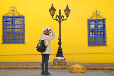 Traveler taking photos of an eye-catching vintage streetlamp with vivid colored building