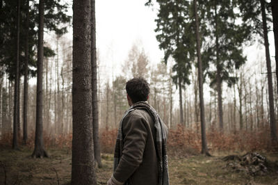 Side view of young man standing in forest