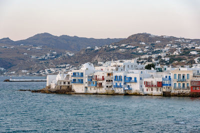 Sea by buildings in city against clear sky