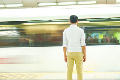 Rear view of man standing at railroad station