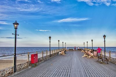 Jetty leading towards sea against blue sky