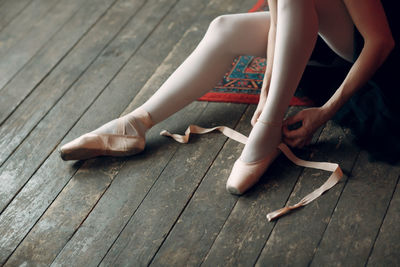 Low section of woman wearing ballet shoe