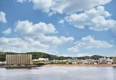 Buildings by sea against sky