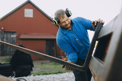 Young farmer with ear protectors installing metal at farm