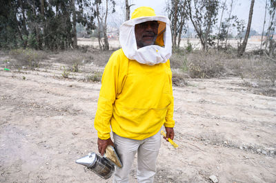 A beekeeper in a protective suit works with bees. 