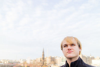 Thoughtful man looking away in city against sky