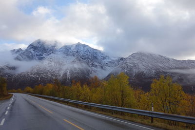 Road leading towards snowcapped mountains against sky