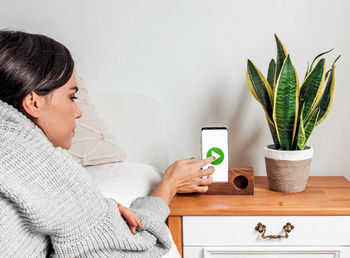 Woman holding mobile phone at home