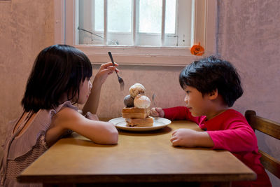 Sisters eating ice cream at table