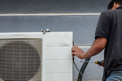 Low angle view of man repairing air conditioner