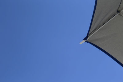 Cropped image of parasol against clear blue sky