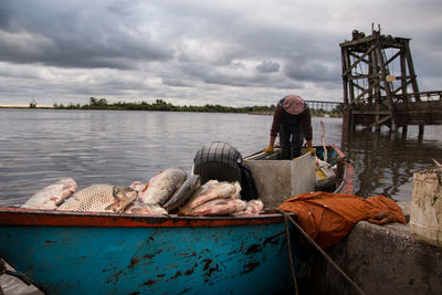 Man standing on boat in river against sky