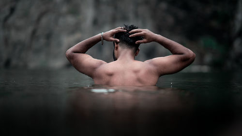 Rear view of shirtless man swimming in water