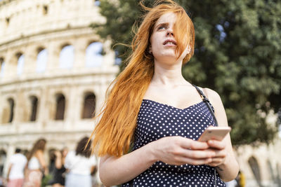 Dreamy tourist with smartphone on street