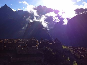 Sun shining through clouds over mountains