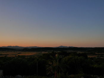 Scenic view of field against clear sky at sunset