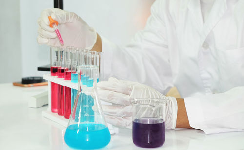 Midsection of scientist holding test tube at laboratory