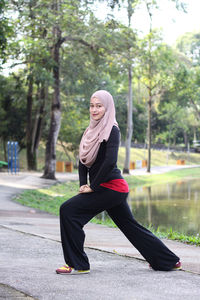 Portrait of mid adult woman wearing hijab while exercising by lake at park