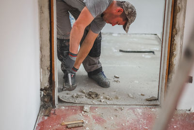 A man dismantles the plinth using a hammer and crowbar.