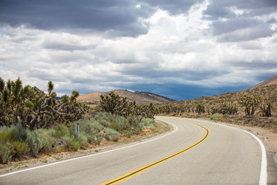 Road leading towards mountains against sky