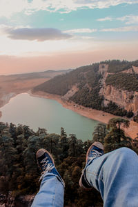 Low section of man on mountain against sky