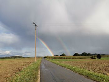 Road amidst field against sky