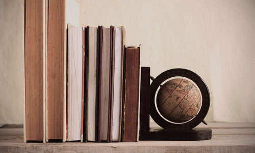 Books and globe against wall on table