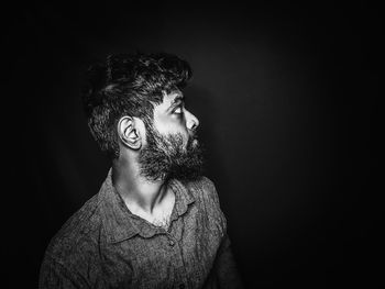 Portrait of young man standing against black background