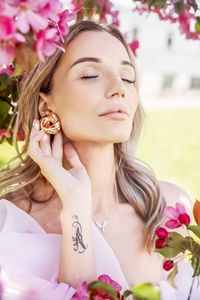 Portrait of a beautiful romantic young woman in close-up with pink flowers of a blooming apple tree. 