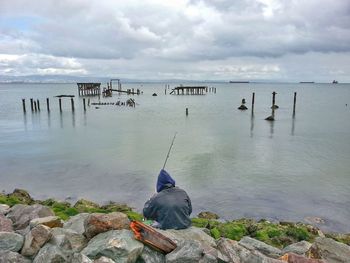 Seagulls perching on wooden post at beach against sky